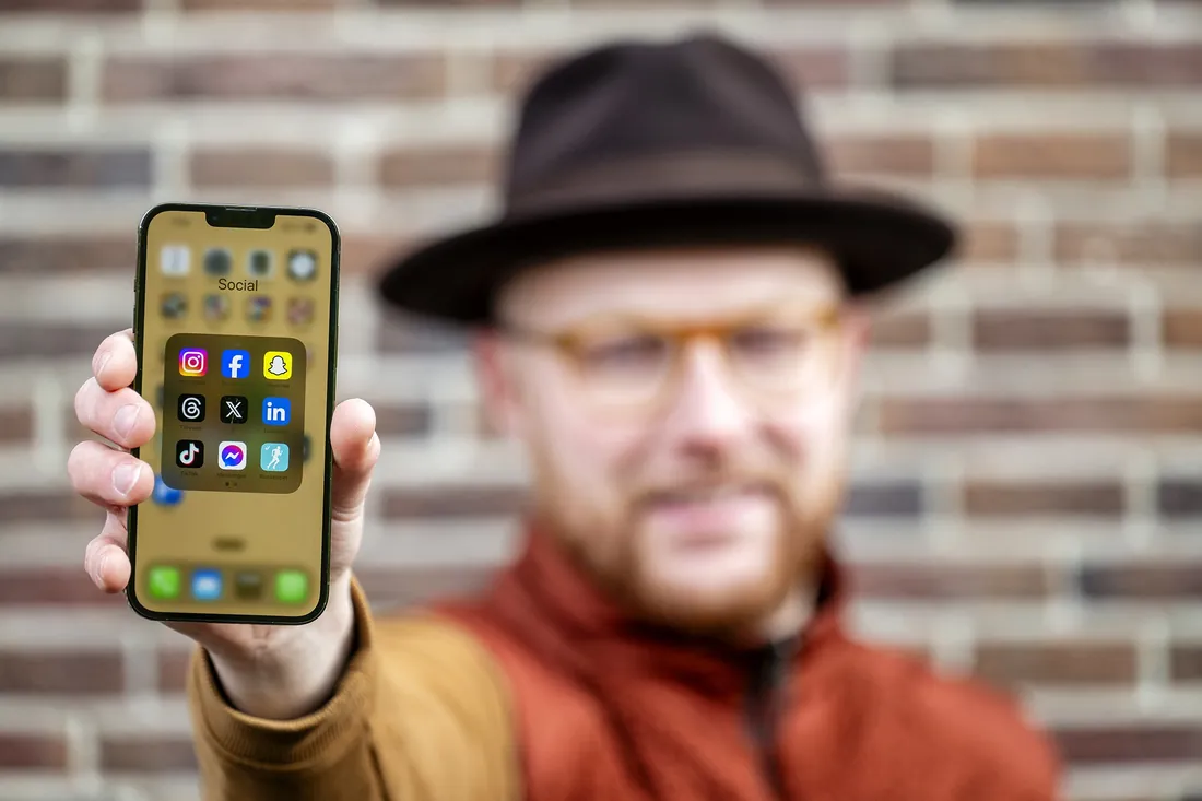 Brent Renniers van Red Flame Marketing met social media-apps op zijn telefoon